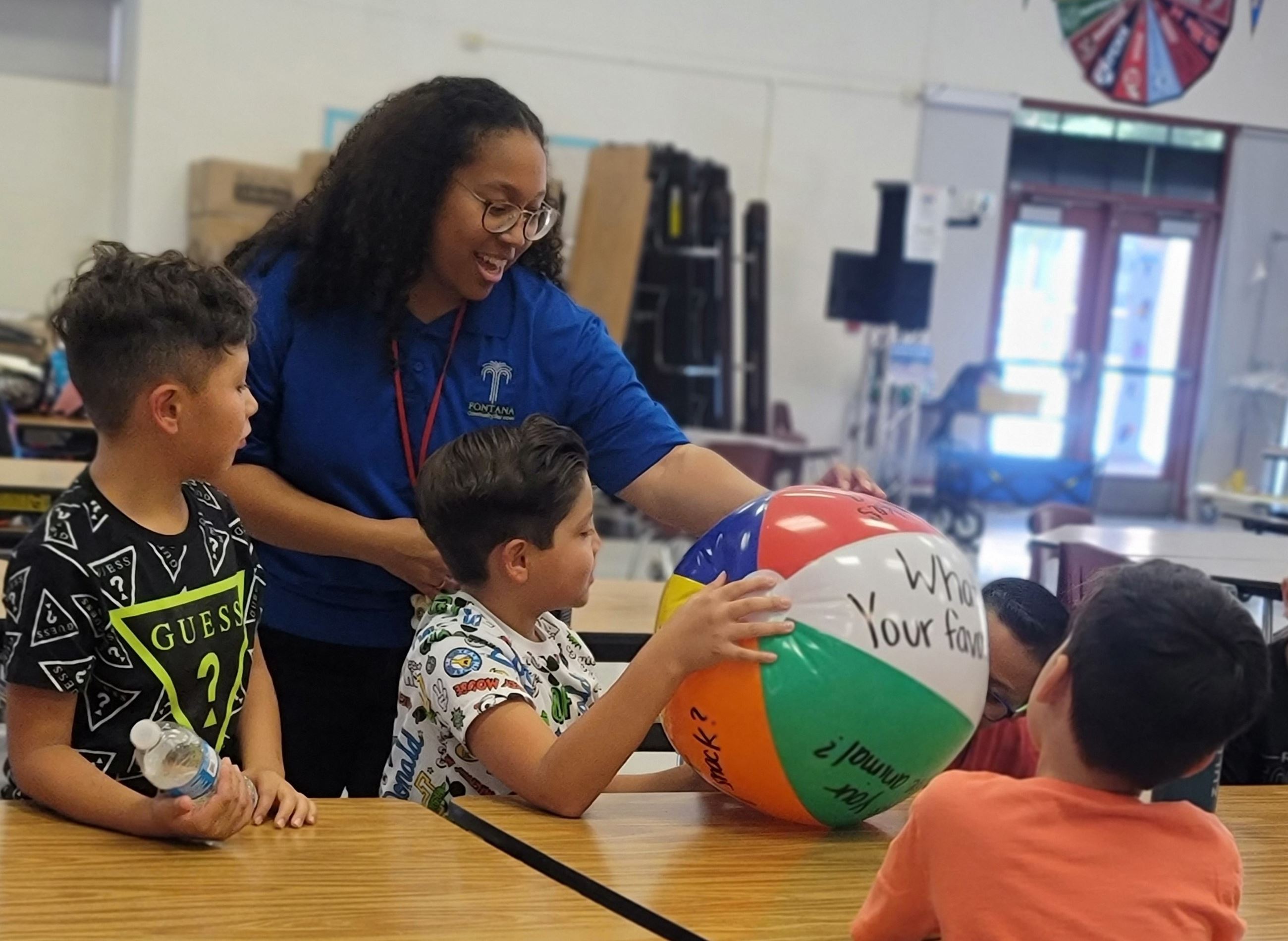 A FELP staff shows students activity ball on a table